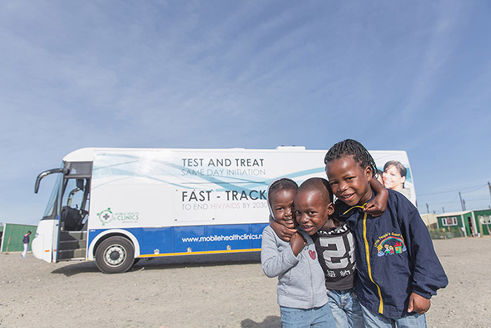 Smiling kids standing outside an HIV mobile clinic